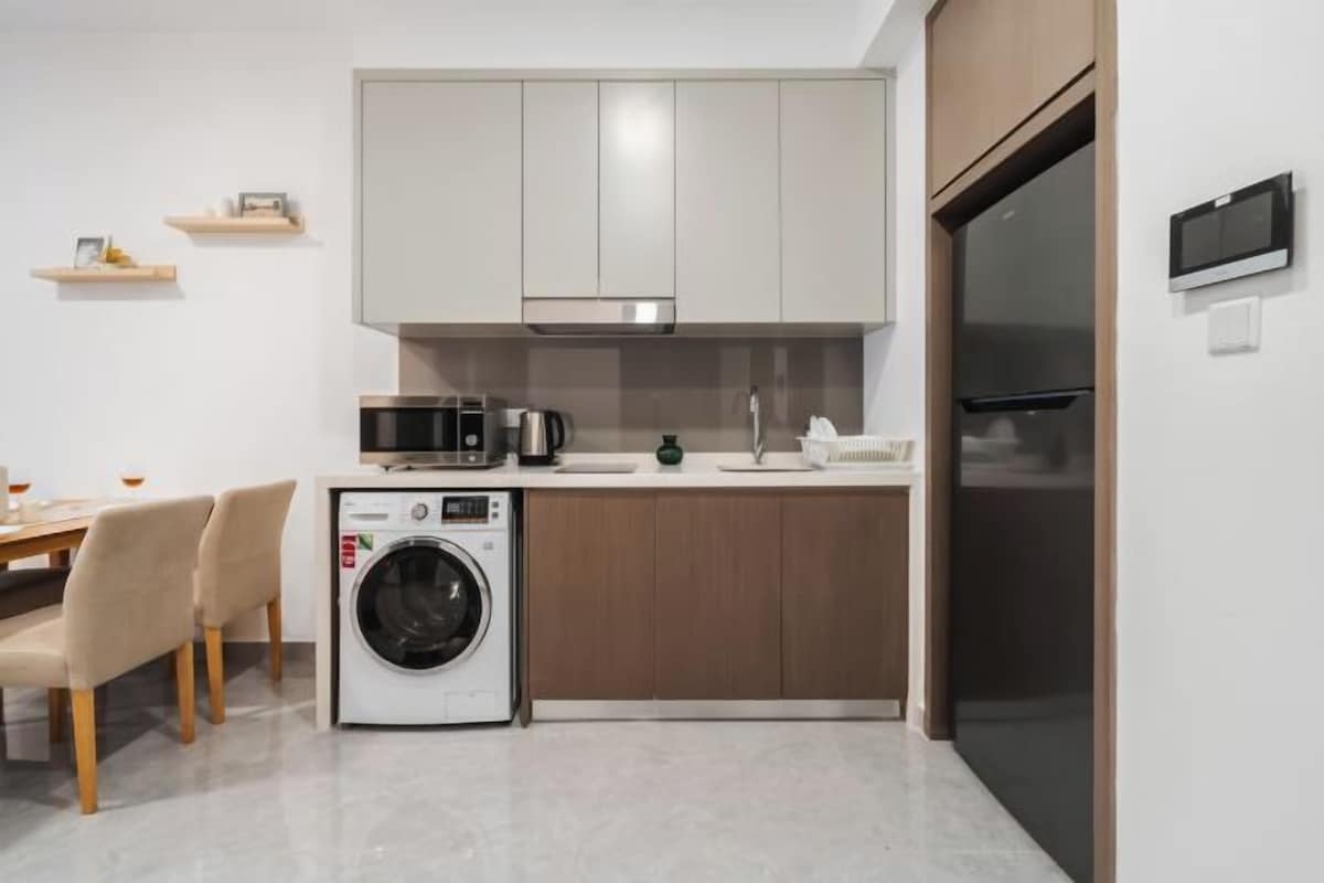 A compact kitchen with a washing machine, microwave, and a refrigerator.