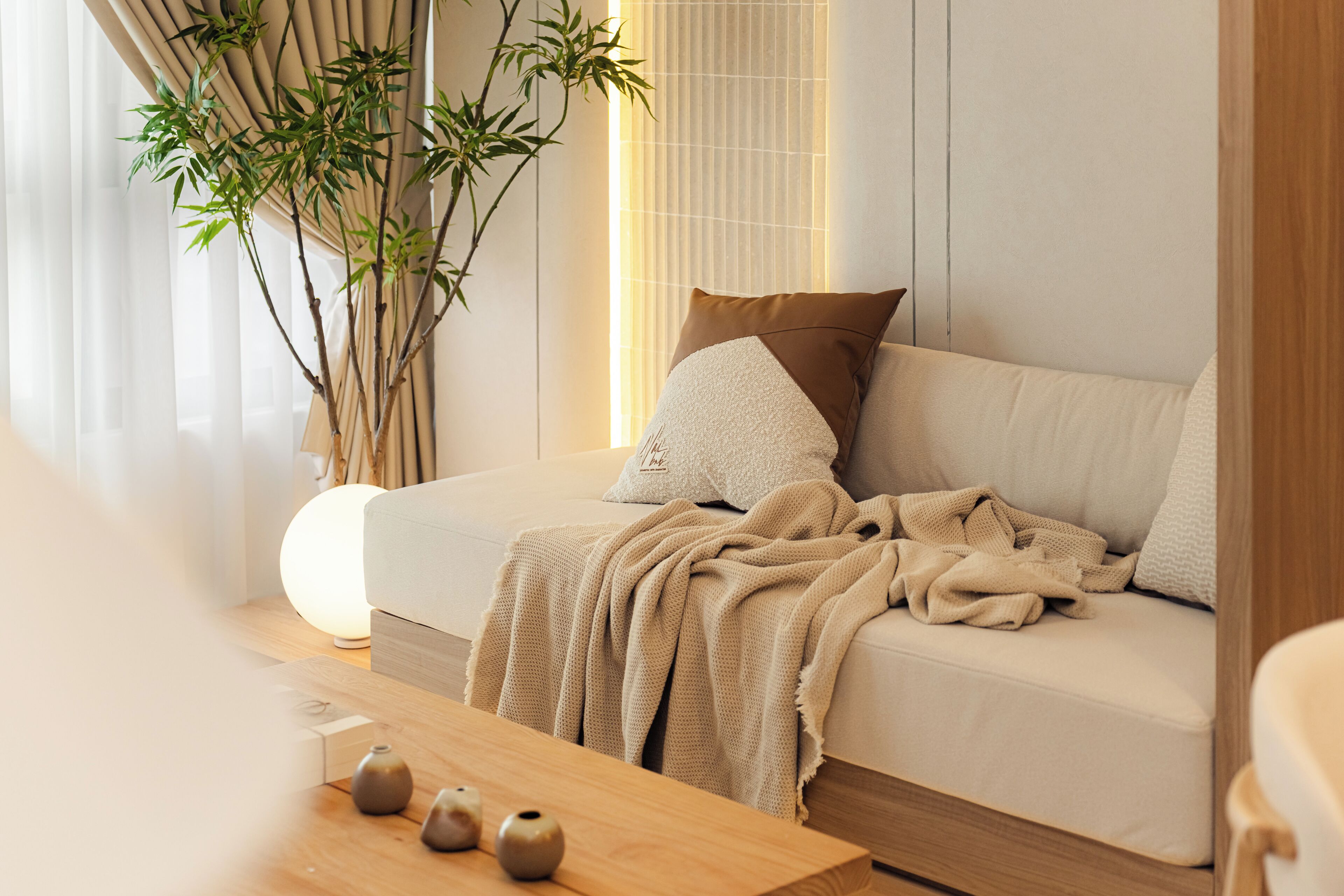 Ein modernes Wohnzimmer mit Sofa, Couchtisch, dekorativen Vasen und einer Bambuspflanze.