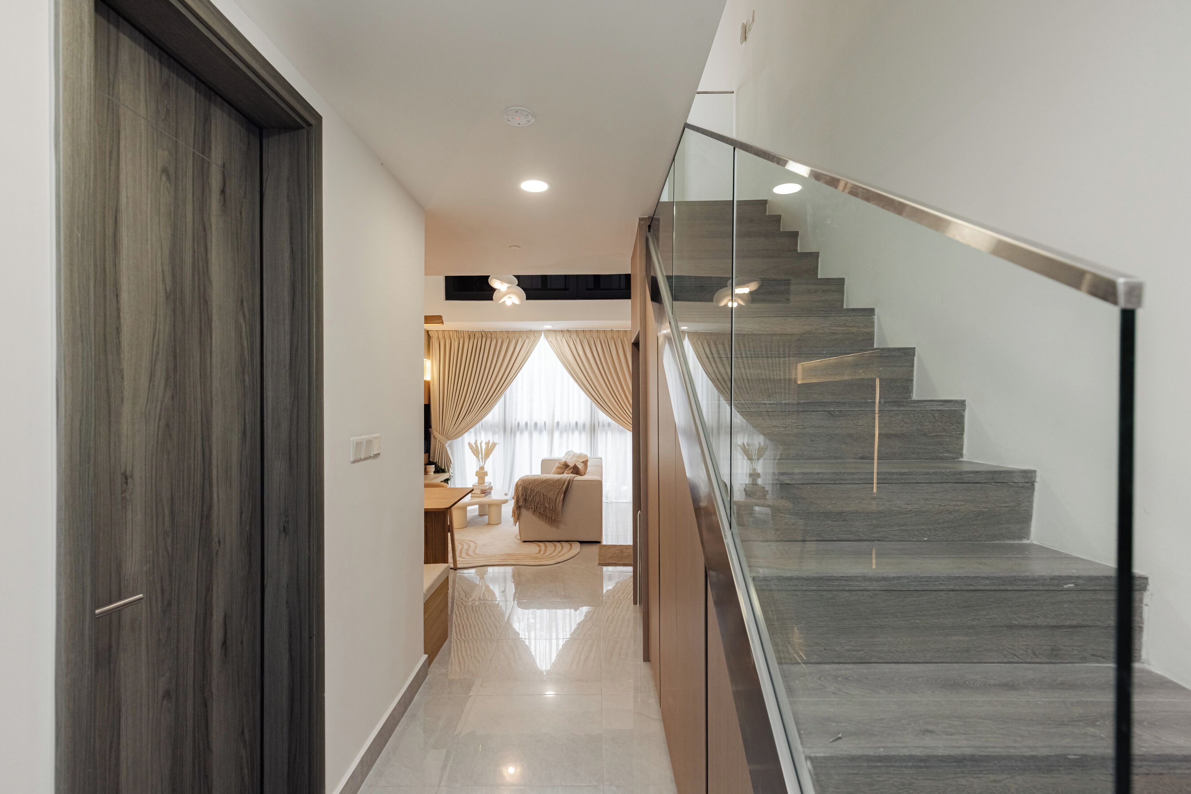 Una escalera moderna con barandillas de cristal y suelo de madera.