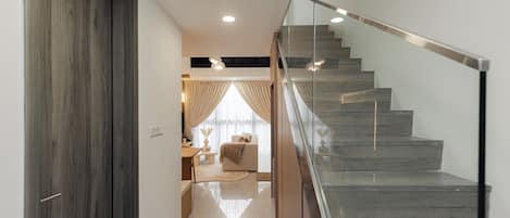 Una escalera moderna con barandillas de cristal y suelo de madera.