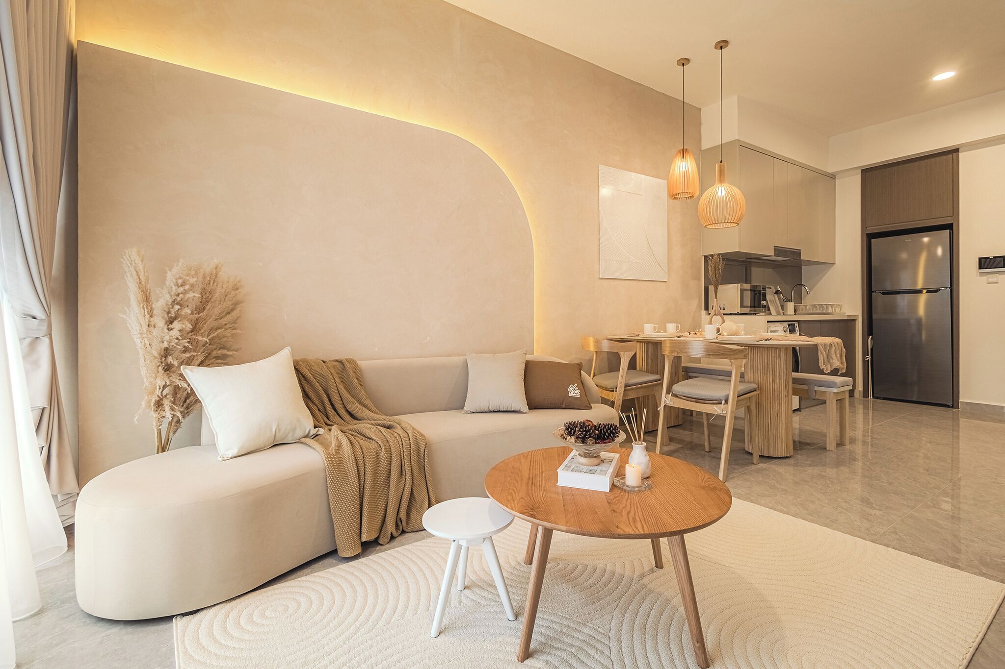 A modern living room with a sofa, a round wooden coffee table, and a dining area with a table and chairs.