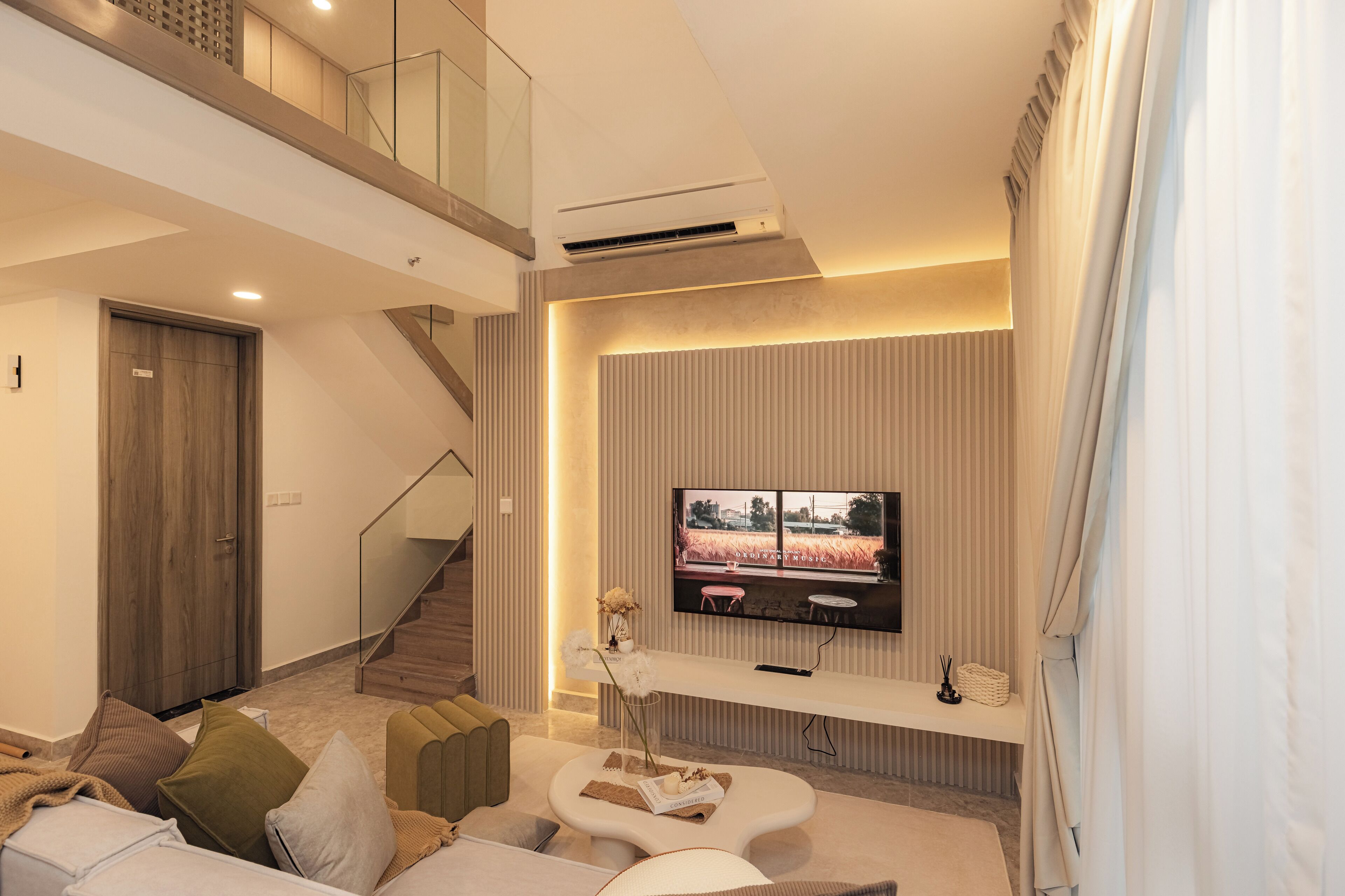 Una sala de estar moderna con un televisor de pantalla plana, una escalera y un rincón de descanso acogedor.