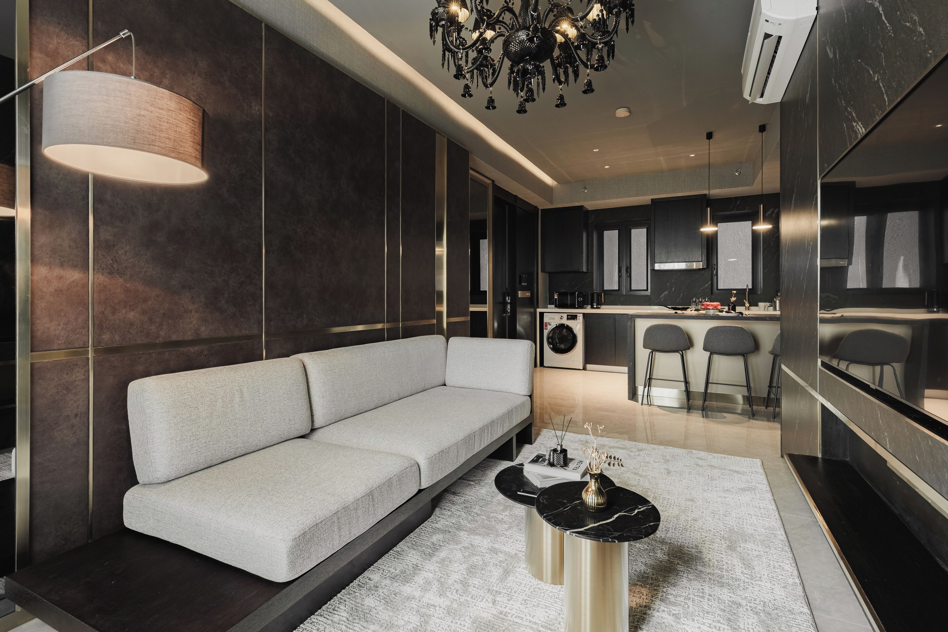 A modern living room with a grey sofa, a black coffee table, and a chandelier.