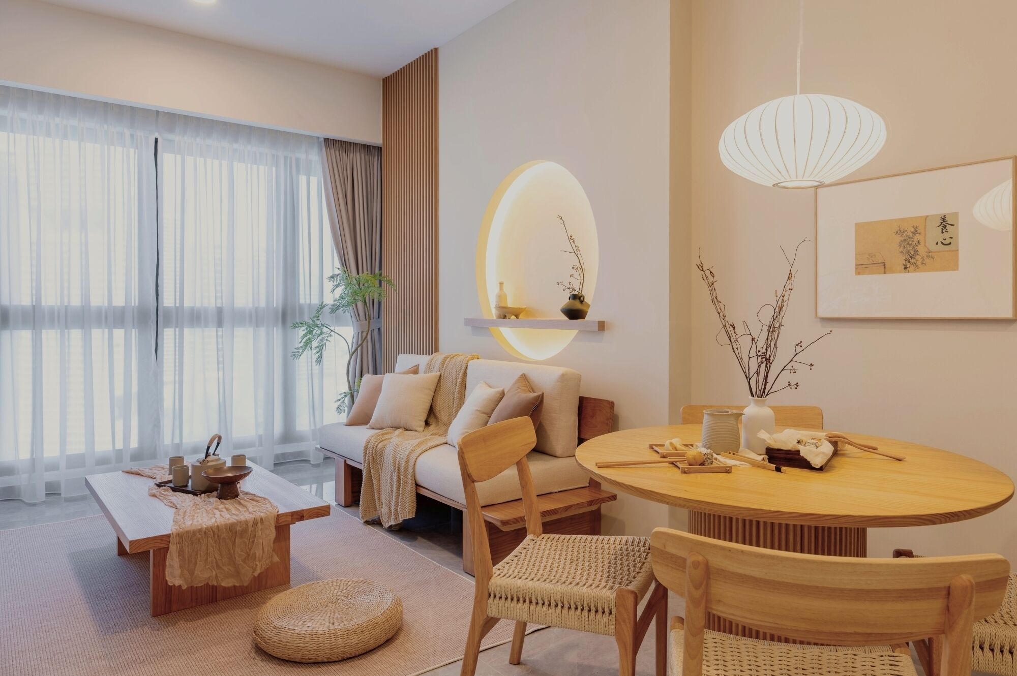 A modern living room with a sofa, a round wooden dining table, a coffee table, and a large window with sheer curtains.