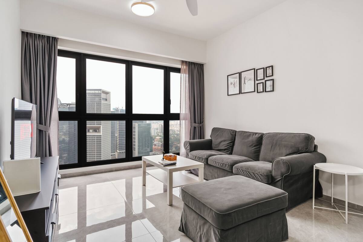 Una sala moderna con un sofá gris, una mesa de centro blanca y una mesita auxiliar pequeña, también blanca.