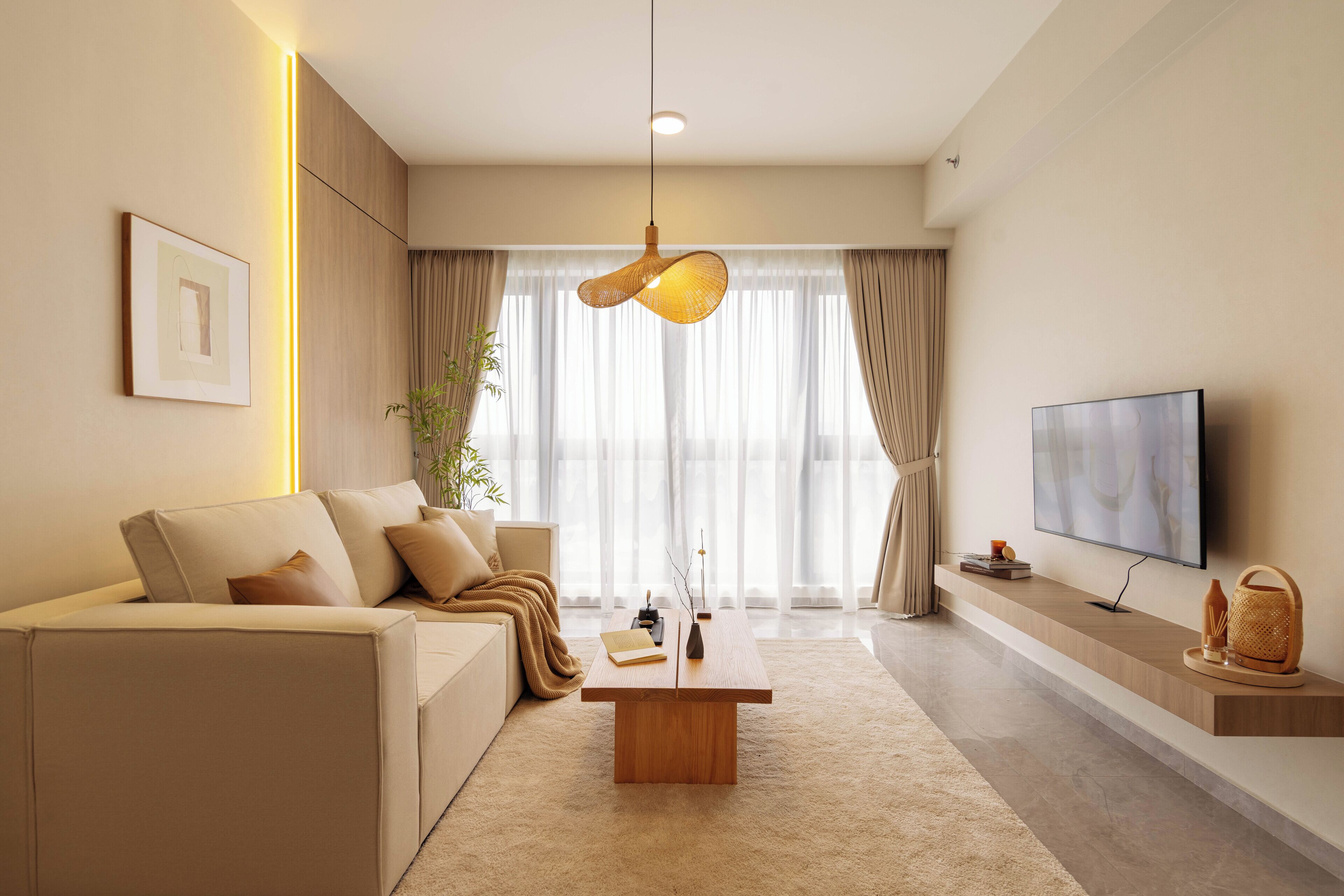 A modern living room with a sofa, a coffee table, a TV, and a plant.