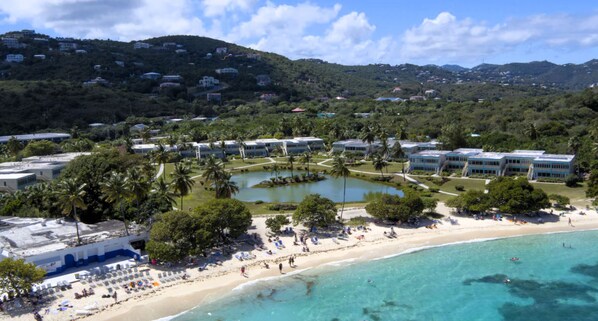 Un complejo turístico frente al mar, con acceso directo a la playa, un área de piscina central y varias edificaciones hoteleras.