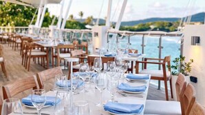 Comedor en un barco con mesas dispuestas para el servicio, con vista al mar.