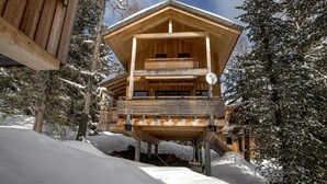 Uma cabana de madeira com varanda, rodeada por árvores cobertas de neve.