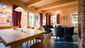 Interior em madeira com mesa de jantar, cadeiras, sofá e lareira.