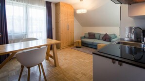 A modern kitchen with a built-in stove, a dining area with a wooden table and chairs, and a cozy seating area with a sofa. - Apartment in Pine Forest Near Ski Slopes (Stadl-Predlitz)
