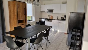 Eine moderne Küche mit Esstisch, Stühlen, einem Kühlschrank und einer Mikrowelle.