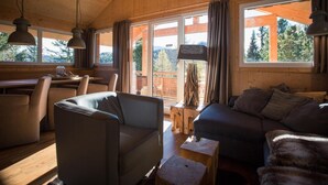 A cozy cabin interior with wooden walls, a dining area, and a seating area with a couch and chairs. - Exclusive Chalet With Sauna (Stadl-Predlitz)