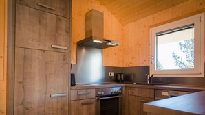 A modern kitchen with wooden cabinetry, a stainless steel range hood, and a window providing natural light. - Exclusive Chalet With Sauna (Stadl-Predlitz)