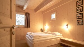 A wooden room with a bed, a window, and wall-mounted lights. - Exclusive Chalet With Sauna (Stadl-Predlitz)