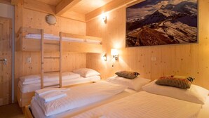 A wooden cabin room with bunk beds, a painting of a mountain landscape, and wall-mounted lights. - Cosy Chalet With Infrared Sauna (Stadl-Predlitz)