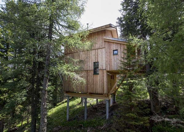 A wooden treehouse elevated on stilts in a forest. - Cosy Chalet With Infrared Sauna (Stadl-Predlitz)