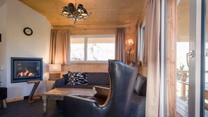 A cozy living room with a fireplace, leather armchair, and a sofa. - Cosy Chalet With Infrared Sauna (Stadl-Predlitz)