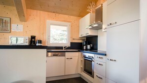 A modern kitchen with white cabinets, a built-in oven, a microwave, and a coffee maker. - Cosy Chalet With Infrared Sauna (Stadl-Predlitz)