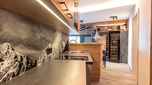 A modern kitchen with a marble backsplash, wooden cabinets, and a wine rack.