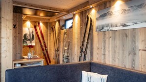 A wooden interior with skis mounted on the wall, a bench, and a table.