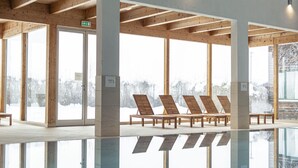 A modern indoor pool area with wooden beams, large windows, and sun loungers. - Holiday Home for 4 People With Gallery (Sankt Georgen am Kreischberg)