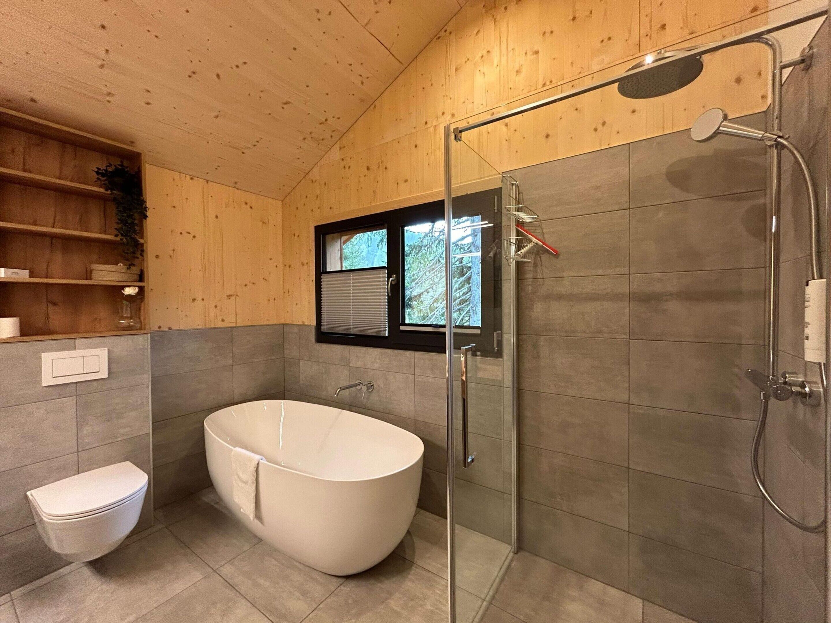 A modern bathroom with a freestanding bathtub, a glass-enclosed shower, and a toilet.
