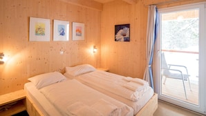 A wooden-paneled room with two beds, a sliding glass door to a balcony, and three framed pictures on the wall. - Lovely Chalet With Sauna (Stadl-Predlitz)