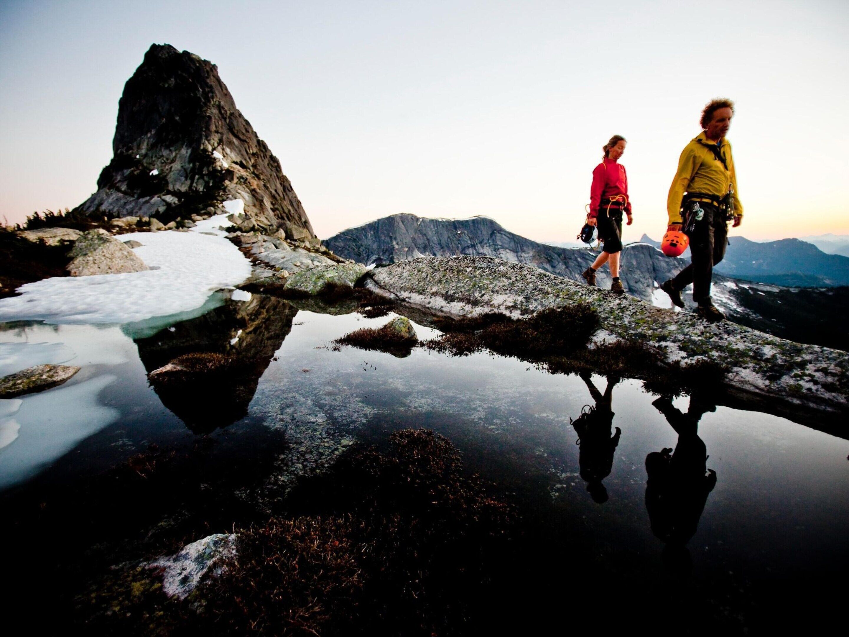 A natural landscape with a reflective water surface, rocky terrain, and mountains in the background.