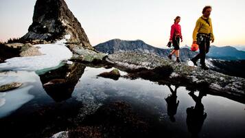 A natural landscape with a reflective water surface, rocky terrain, and mountains in the background.