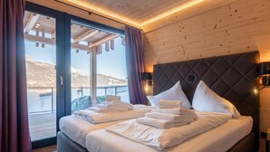 Une chambre avec un lit, une vue sur un paysage enneigé et des murs en bois.