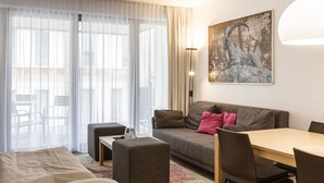 A modern hotel room with a sofa, ottoman, and a dining table. - Apartment Near Ski Slope (Schladming)