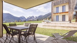 A wooden deck with a table and chairs, overlooking a mountainous landscape. - Apartment Near Ski Slope (Schladming)