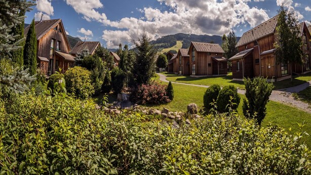 A row of wooden cabins with a clear sky and mountains in the background. - Welcoming Chalet With Terrace (Sankt Georgen am Kreischberg)