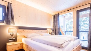 A wooden bedroom with a bed, nightstands, and a window. - Inviting Chalet With Indoor Sauna (Stadl-Predlitz)