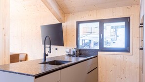 A modern kitchen with wooden walls, a large window, and a built-in sink. - Inviting Chalet With Indoor Sauna (Stadl-Predlitz)