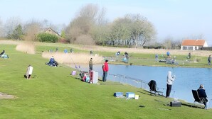 A lakeside area with people fishing, a small house, and a grassy field. - Holiday Home With Pet-friendly Garden (Breskens)