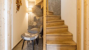 Een houten trap die leidt naar een stenen muur, een gestreept fauteuil en een vloerlamp.
