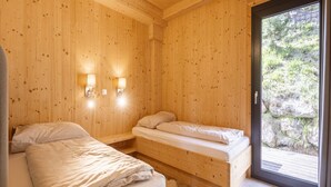 Een houten kamer met twee bedden, een raam en wandlampen.