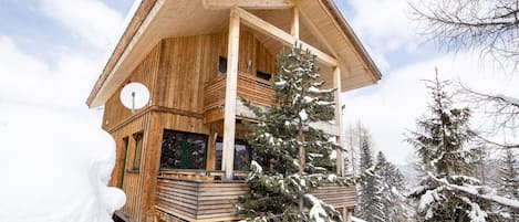 Un chalet de madera con techo inclinado, un balcón y una antena parabólica.