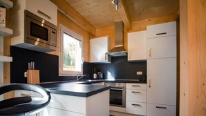 Une cuisine moderne avec des meubles blancs, un four en acier inoxydable et un plan de travail noir.