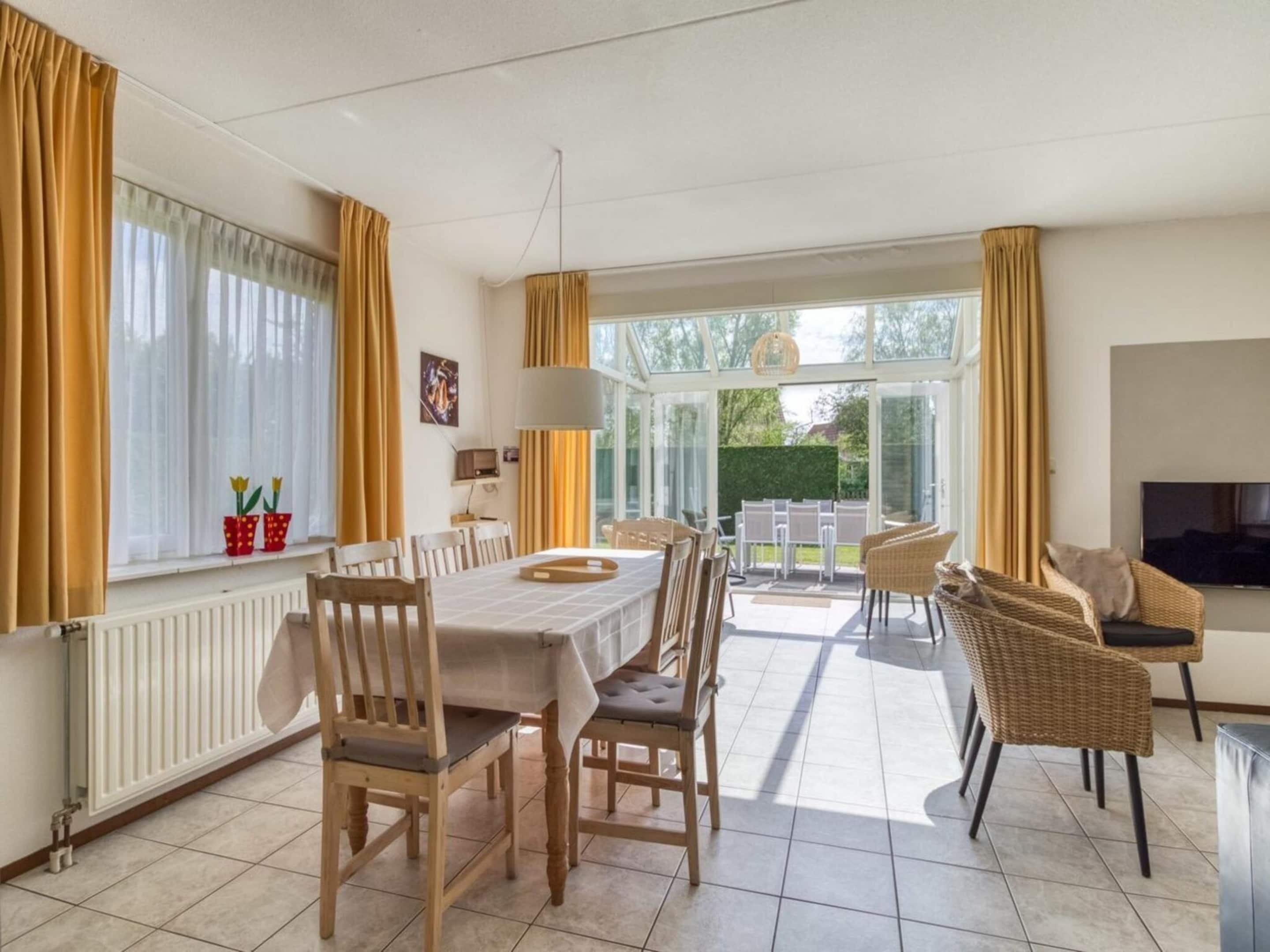 A dining area with a table and chairs, a television, and a view of the outdoors.