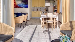 Ein Essbereich mit Tisch und Stühlen, im Hintergrund eine Küche und ein Gemälde an der Wand.