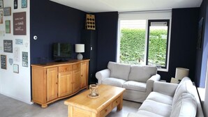 Un salon avec un meuble en bois, un téléviseur, un canapé blanc et une table basse.