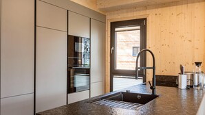 A modern kitchen with a built-in oven, a stainless steel sink, and wooden paneling. - Appealing Chalet With Balcony (Stadl-Predlitz)