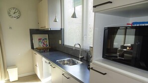 A compact kitchen with a sink, cabinets, and a microwave. - Family Stay - Near Beach (Breskens)