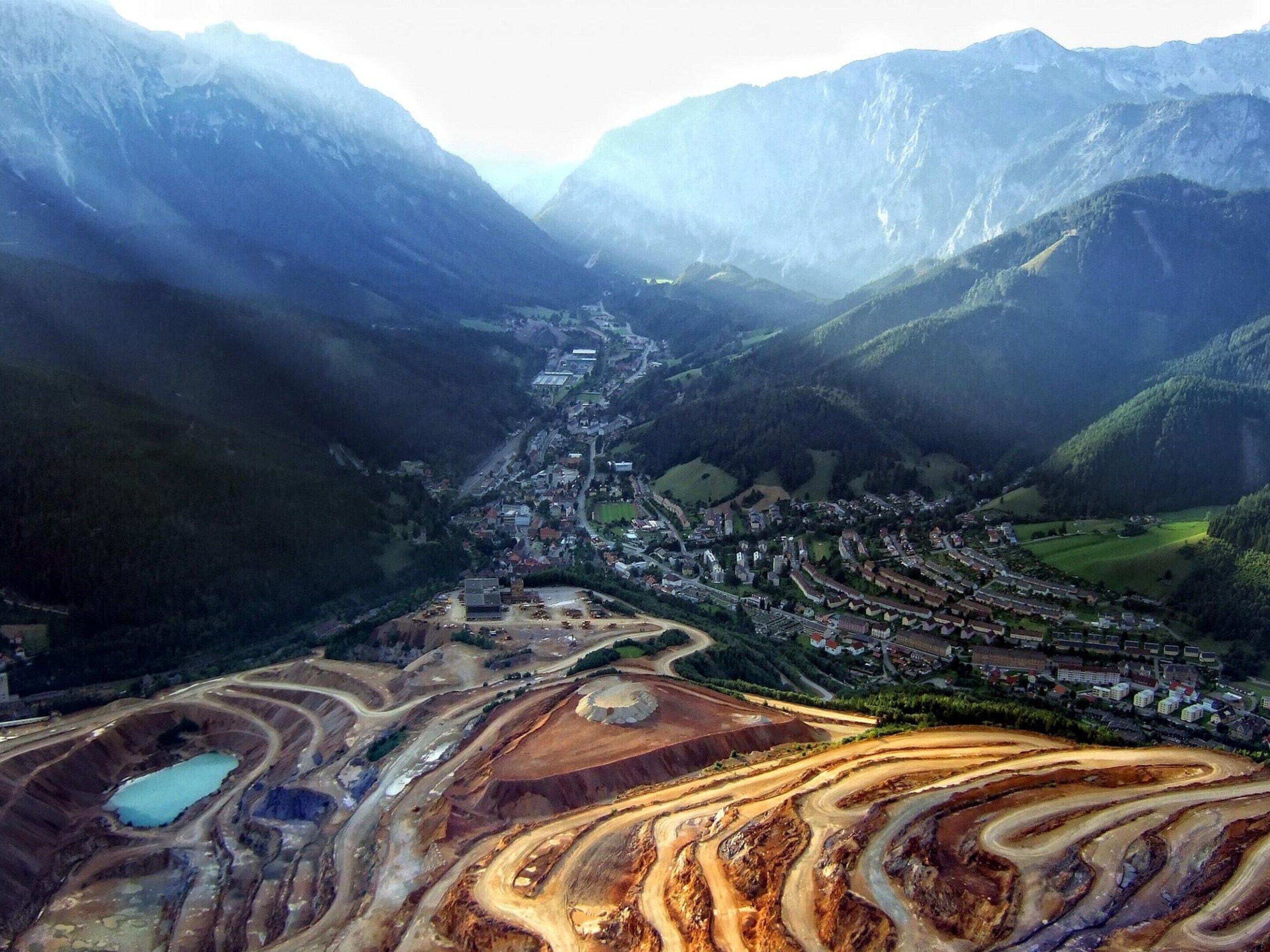 Paisaje montañoso con un valle, un pueblo pequeño y actividades mineras.