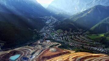Paisaje montañoso con un valle, un pueblo pequeño y actividades mineras.