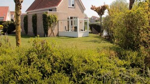 Une maison avec un toit en pente, un porche bien visible à l’avant et une pelouse bien entretenue.
