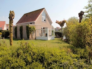 Une maison avec un toit en pente, un porche bien visible à l’avant et une pelouse bien entretenue.